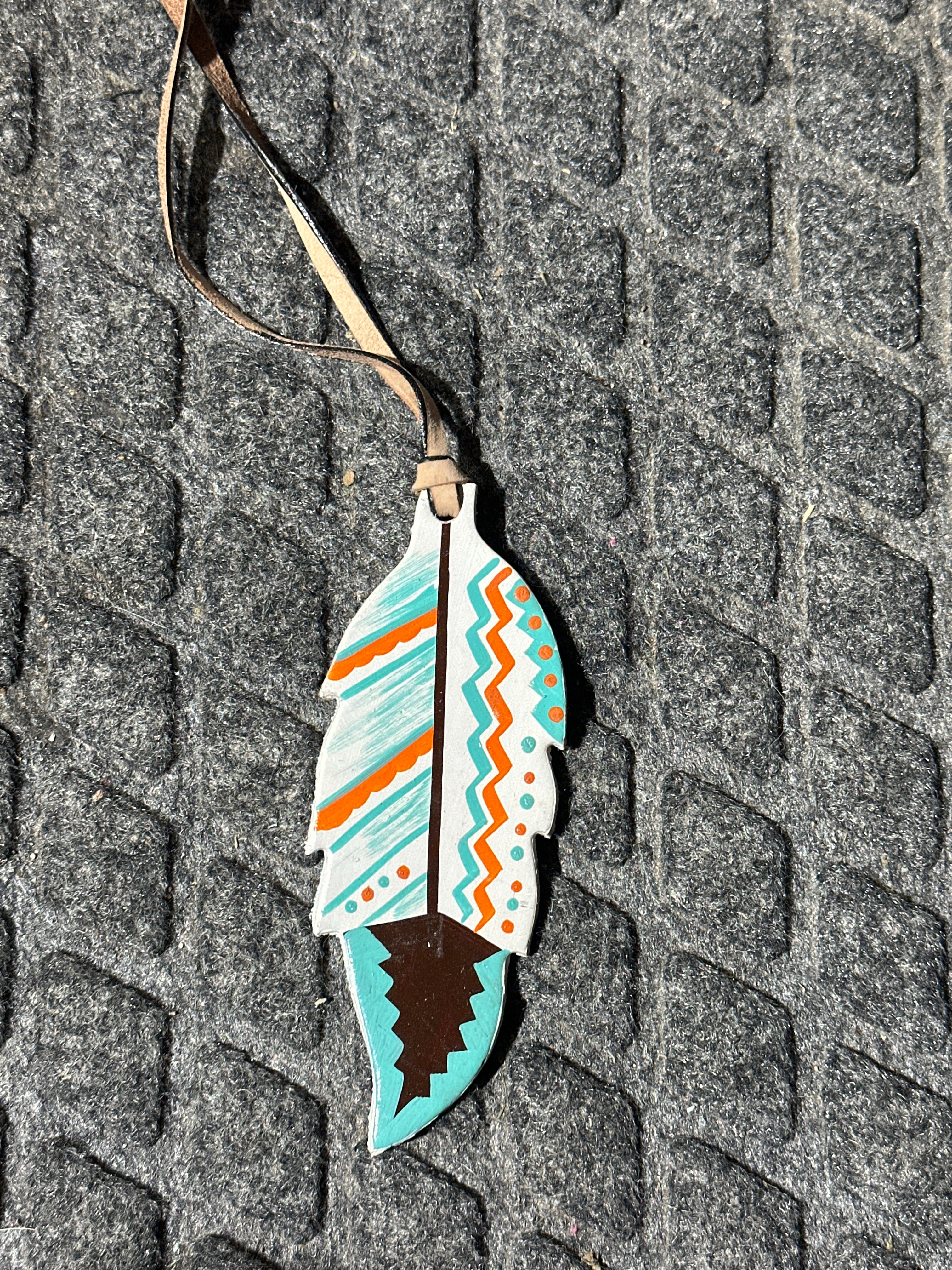 Orange/white/turquoise painted feather tie on saddle charm